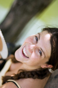 Brunette woman looking up at the camera over her left shoulder and smiling